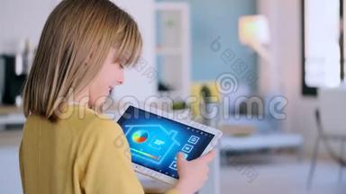 小女孩站在家里时使用带有数字平板电脑的domotic系统。